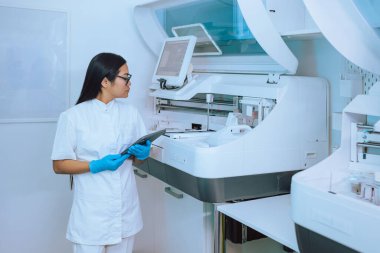 Tablet ve yüksek teknoloji kullanan klinik laboratuvar araştırmacısı, otomatik örnek işleme analizcisi. Tıp yenilik kavramı.