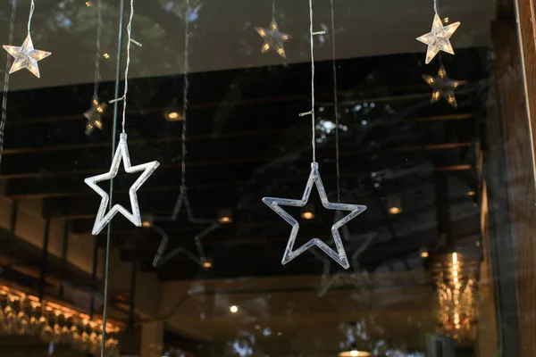 Christmas golden star illumination decoration in front of coffee shop. Holiday market in city street. Christmas and New year concept.