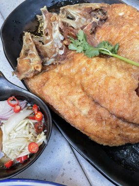 Baharatlı sos ile servis edilen balık soslu kızarmış levrek dilimlenmiş yeşil mango ve limon suyu..