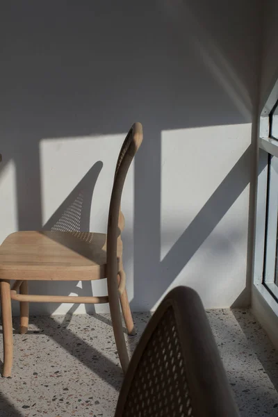 Wooden chair in white room with shadow from the sun through the window. Minimalism style in horizontal.