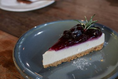Yabanmersinli cheesecake. İçinde taze böğürtlen ve üstünde yabanmersini reçeli var. Masada lezzetli bir tatlı var. Kahve dükkanında taze tatlının tadını çıkarın..