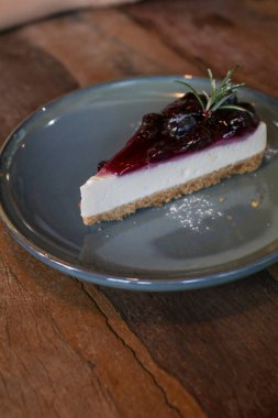 Yabanmersinli cheesecake. İçinde taze böğürtlen ve üstünde yabanmersini reçeli var. Masada lezzetli bir tatlı var. Kahve dükkanında taze tatlının tadını çıkarın..