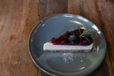 Yabanmersinli cheesecake. İçinde taze böğürtlen ve üstünde yabanmersini reçeli var. Masada lezzetli bir tatlı var. Kahve dükkanında taze tatlının tadını çıkarın..