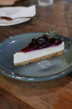 Yabanmersinli cheesecake. İçinde taze böğürtlen ve üstünde yabanmersini reçeli var. Masada lezzetli bir tatlı var. Kahve dükkanında taze tatlının tadını çıkarın..