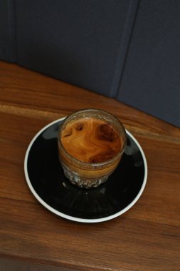 Kahve dükkanındaki ahşap masada kirli kahve. Soğuk taze sütün üzerine ekspresso içmek değişim katmanı oluşturur. Sabah kahvaltısı.