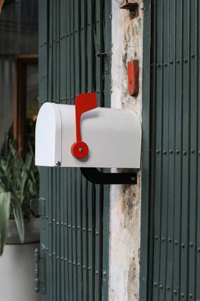 White Mail Box with red with an open door in Front of a House. Envelope and newsletter.