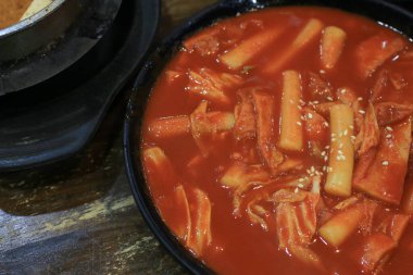 Tteokbokki in black plate. Korean rice cake stick in spicy sauce Korean cuisine dish. Street food