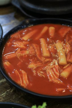 Tteokbokki in black plate. Korean rice cake stick in spicy sauce Korean cuisine dish. Street food