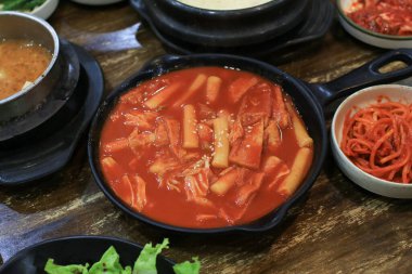 Tteokbokki in black plate. Korean rice cake stick in spicy sauce Korean cuisine dish. Street food