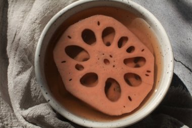 Beyaz kasede şerbetli soğuk nilüfer kökü. Tayland tatlısı. Nilüfer kökü eşsiz bir özelliğe sahiptir. Bu da sağlığa iyi gelir.