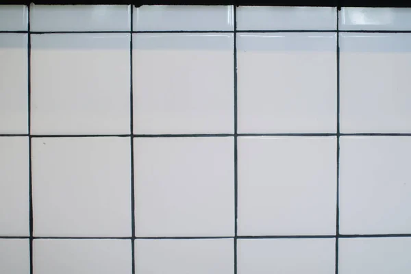 White grid tile wall. Background for wallpaper, patter and tile texture.  Empty kitchen or toilet interior room with square mosaic surface, ceramic tiled grid pattern.