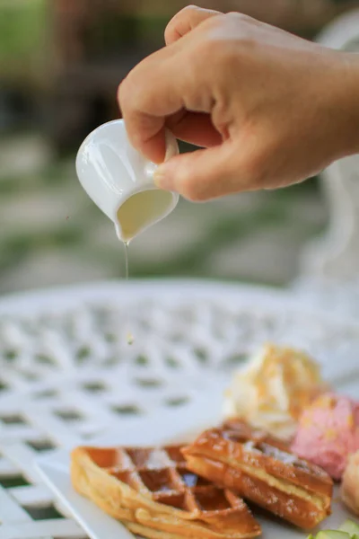 Mão Derramando Xarope Bordo Waffle Sorvete Com Maçã Mesa Branca — Fotografia de Stock