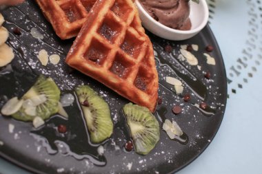 Kiviyle el kesimi waffle ve siyah tabakta dondurma. Ballı waffle. Tatlıyı dene. Ev yapımı sağlıklı kahvaltı.