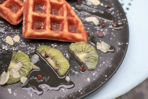 Tangan Memotong Wafel Dengan Kiwi Dan Krim Piring Hitam Waffle — Stok Foto