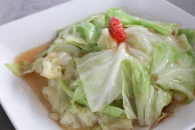 Beyaz zemin üzerinde balık soslu kızarmış lahana. Beyaz kare tabağı. Ev yapımı Asya yemekleri..