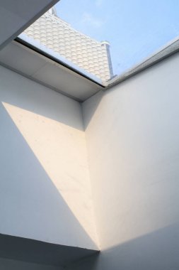 Parlak güneş ışığıyla camdan bir gökyüzü inşa etmek. Büyük pencereli beyaz bir duvar. Parlayan evde güneşli bir gün.