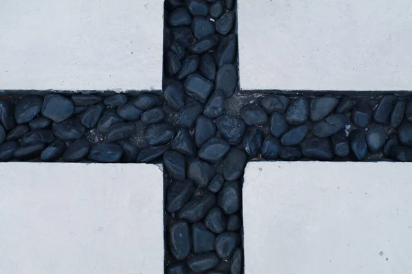 中央の十字線との間に黒い石を持つ白いコンクリートブロック床 抽象幾何学模様のテクスチャの背景 — ストック写真