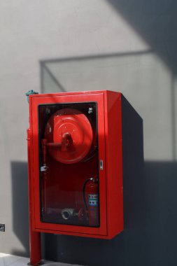 Beton duvarda güneş ışığı altında kırmızı yangın söndürme sistemi. Yangın güvenliği. Endüstriyel acil durum ekipmanları