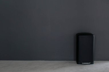 Gri arkaplanda kopyalama alanı olan siyah çöp. Modern iç tasarım. Temizlik konsepti. Çöp kutusu mermer zeminde..