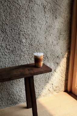 Buzlu kapuçino kahvesi. Soğuk yaz içkisi. Sabahın erken saatlerinde güneş. Karanlık ahşap arka planda fotokopi alanı olan soğuk yaz içeceği..