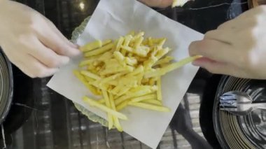 Elleri tabaktan peynir soslu patates kızartması alıyor. Arkadaşla hafta sonu partisi. Yemeğin tadını çıkarıyorum. Fast food konsepti.