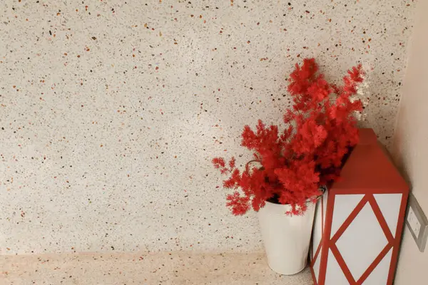Red flower in white vase on wooden table. House plant in flowerpot. Holiday, interior decoration. Minimal style.