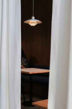 Tavan lambalı ahşap yuvarlak masa ve cafe veya restoran dekorasyonunda beyaz perde. Görünüm, Arkaplan ve Duvar Kağıdı.