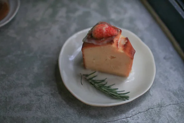 Basque burnt cheesecake with fresh strawberries on white plate cement floor background. Japanese desser.