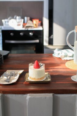 Tahta masada güneş ışığıyla taze çilekli cheesecake. Lezzetli ve basit bir pasta. Ev yapımı tatlı..