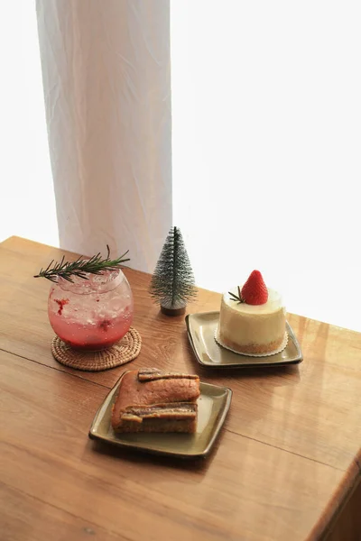 Mixed berry Mojito soda with strawberry cake and banana bread on wooden table with christmas tree. Refreshing cool drink and bakery.