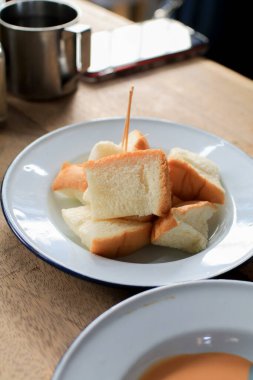 Hafif kızartılmış beyaz ekmek parçaları. Tahta masada beyaz tabakta. Sabah kahvaltısı. Kahve ve tatlı konsepti.