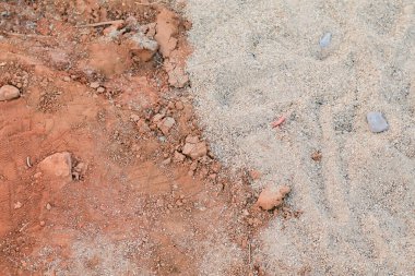 Kırmızı ve gri çakıl toprak yol. Zeminin taşlı dokuları. Arka planda çatlak olan kuru toprak. Kara yüzeyini kapat.