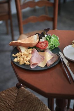 Amerikan kahvaltı yumurtası, jambon, sosis, pastırma, domates, ekmek ve salata. Sabahları sağlıklı besleniyorlar..