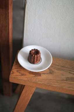 Bordo Caneles de Bordeaux, beyaz tabakta, ahşap masada. Geleneksel Fransız tatlısıyla çay ya da kahve..