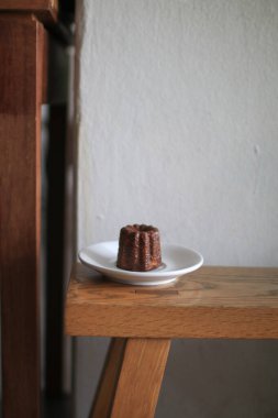 Bordo Caneles de Bordeaux, beyaz tabakta, ahşap masada. Geleneksel Fransız tatlısıyla çay ya da kahve..