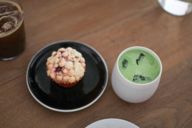 Cafe 'deki ahşap masada yeşil çay, sütlü latte. Japon geleneksel seramik kasesi. Çeşit çeşit tatlı fırın ve pastane-