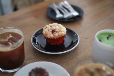 Kafedeki ahşap masada siyah tabakta kırmızı kadife kekler. Sevgililer Günü için ev yapımı tatlı ve fırın.