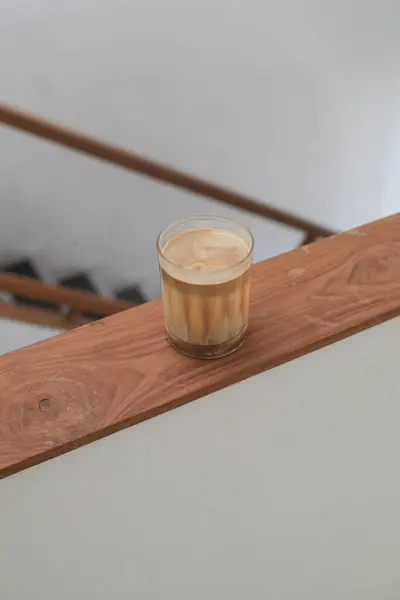 Dirty coffee placed on wooden board. Glass of espresso shot mixed with cold fresh milk in coffee shop cafe and restaurant