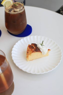 Beyaz tabakta kremalı Bask peynirli keki. Kafedeki masada bir dilim kek. Tatlı. Ev yapımı tarifle taze pişmiş..