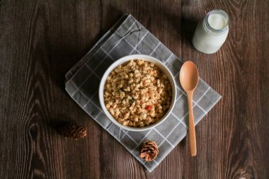 Kuru üzümlü, kızılcıklı ve fındıklı granola kahvaltısı. Tahta masadaki beyaz kasede sütle servis ediliyor. Sağlıklı beslenme.