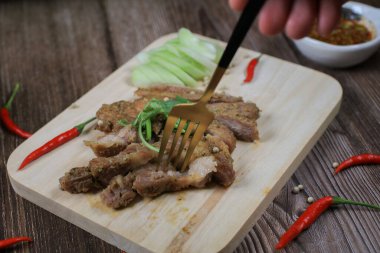 Mangalda domuz budu yiyen ahşap tahtaya baharatlı sos bandıran Tayland 'da popüler aperatif.