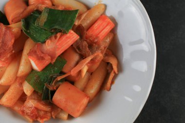 Tteokbokki, siyah zemin üzerinde pirinç keki ve baharatlı sos bulunan bir Kore mutfağıdır. Asya yemekleri. Üst Manzara. Boşluğu kopyala