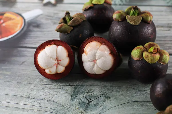 Ahşap arka planda izole edilmiş Mangosteen. Meyve Kraliçesi olarak bilinen Asya meyveleri konsepti. Tatlı tropikal meyve.