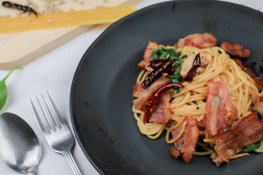 Kurutulmuş biberli spagetti, fesleğen ve pastırma beyaz masada. Geleneksel Popüler menü klasik İtalyan mutfağı. Lezzetli baharatlı yemekler..