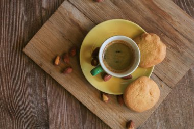 Yeşil fincanda kahve ve ahşap masada kurabiyeler. Kırsal ahşap arka plan. Sıcak bir sabah kahvaltısı evde ya da kafede.