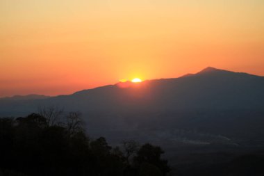 Sis, gökyüzü ve bulutla dağların üzerinde güzel bir gün doğumu. Taze ve rahat doğa manzarası. Dramatik açık hava sahnesi
