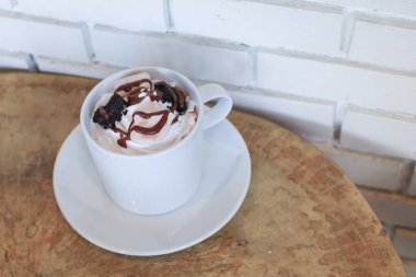 Sıcak çikolata, ahşap masada beyaz fincanda krema ile servis edilir. Noel ve yeni yıl tatlı içeceği ve yemek tatili konsepti