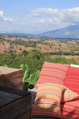 Sabahları dağ manzaralı kırmızı yastıklı Tayland tarzı ipek desenli. Dışarıda, balkon terasında. Tatilde seyahat.