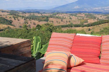 Sabahları dağ manzaralı kırmızı yastıklı Tayland tarzı ipek desenli. Dışarıda, balkon terasında. Tatilde seyahat.