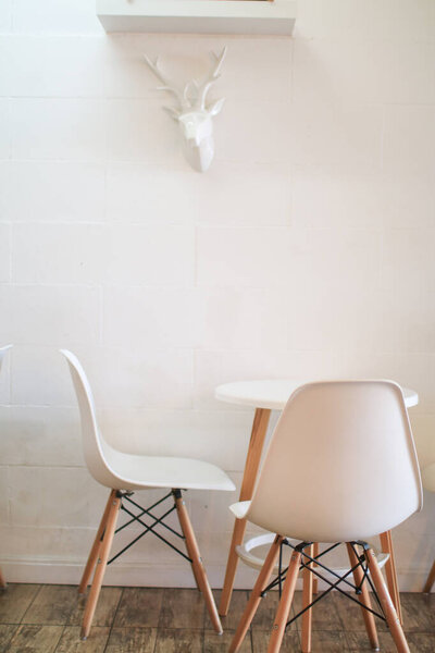Modern white table and chair on wooden floor in cafe. Minimalist interior design decoration. Empty living room.